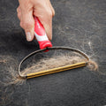 IndigoPro lint and pet hair remover from IndigoPetco.com shown in use, designed to clean pet hair and lint from clothing and upholstery.